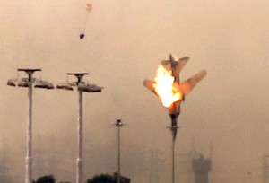 A parachute (L) is ejected from a Libyan jet bomber as it crashes after being hit over Benghazi on March 19, 2011 as Libya's rebel stronghold came under attack, with at least two air strikes and sustained shelling of the city's south sending thick smoke into the sky. AFP PHOTO/PATRICK BAZ (Photo credit should read PATRICK BAZ/AFP/Getty Images)