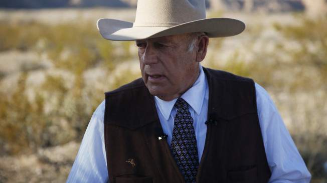 In this Jan. 27, 2016, file photo, rancher Cliven Bundy stands along the road near his ranch Wednesday, Jan. 27, 2016, in Bunkerville, Nev. Bundy, the father of the jailed leader of the Oregon refuge occupation and who was the center of a standoff with federal officials in Nevada in 2014, was arrested in Portland Wednesday night. (AP Photo/John Locher)