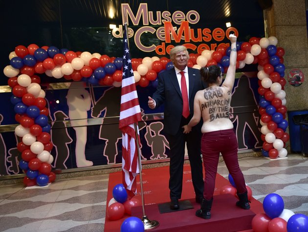 EDITORS NOTE: Graphic content / A topless Femen activist with a sign painted on her back raises her fist as she protests in front of the wax statue of US President-elect Donald Trump at the Wax Museum of Madrid on January 17, 2017. / AFP / GERARD JULIEN        (Photo credit should read GERARD JULIEN/AFP/Getty Images)