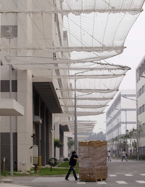 A worker pushes a trolley carrying products under nets which are installed on a factory building to prevent workers from jumping to their deaths at a Foxconn factory in Langfang, Hebei Province August 3, 2010. Taiwan's Hon Hai Precision Industry Co Ltd , also known as Foxconn Technology Group, opened a new $100 million production factory in the central Chinese province of Henan, as the group began to move production inland in a bid to cap rising labour costs, according to a state media report. REUTERS/Jason Lee (CHINA - Tags: BUSINESS)