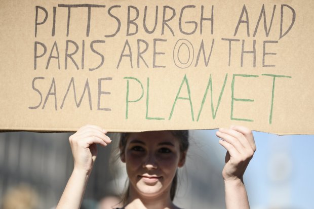 epa06006354 A protestor holds a sign reading 'Pittsburgh and Paris are on the same planet' in front of Brandenburg Gate near the US embassy, during a protest against the US pullout of the Paris Climate Accord in Berlin, Germany, 02 June 2017. US President Donald Trump's 01 June 2017 announcement that the US is withdrawing from the Paris (climate) accord has led to widespread international condemnation.  EPA/CLEMENS BILAN